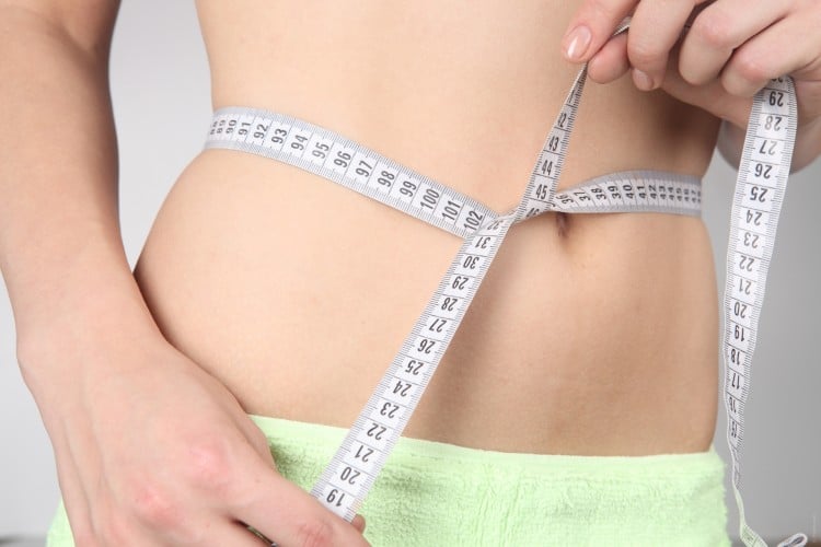 Žena, která si měží váhový úbytek v oblasti břicha