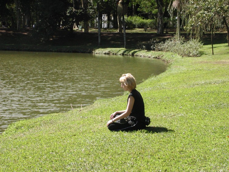 Meditující žena na břehu rybníka