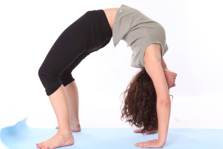 Žena cvičí pozici mostu na modré podložce na jógu