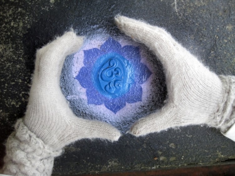 Lidské ruce v bílých rukavicích svírají modrý lotosový symbol